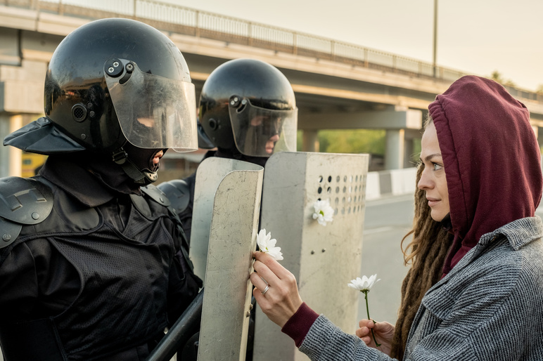 Peaceful woman protester with riot police shutterstock 2006300324