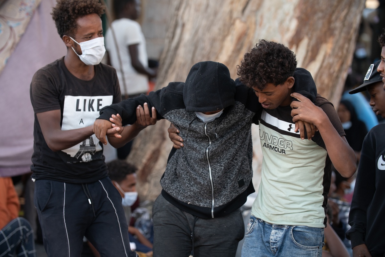 Libya Two migrants helping a wounded man Tripoli Oct 2021 shutterstock 2143922593