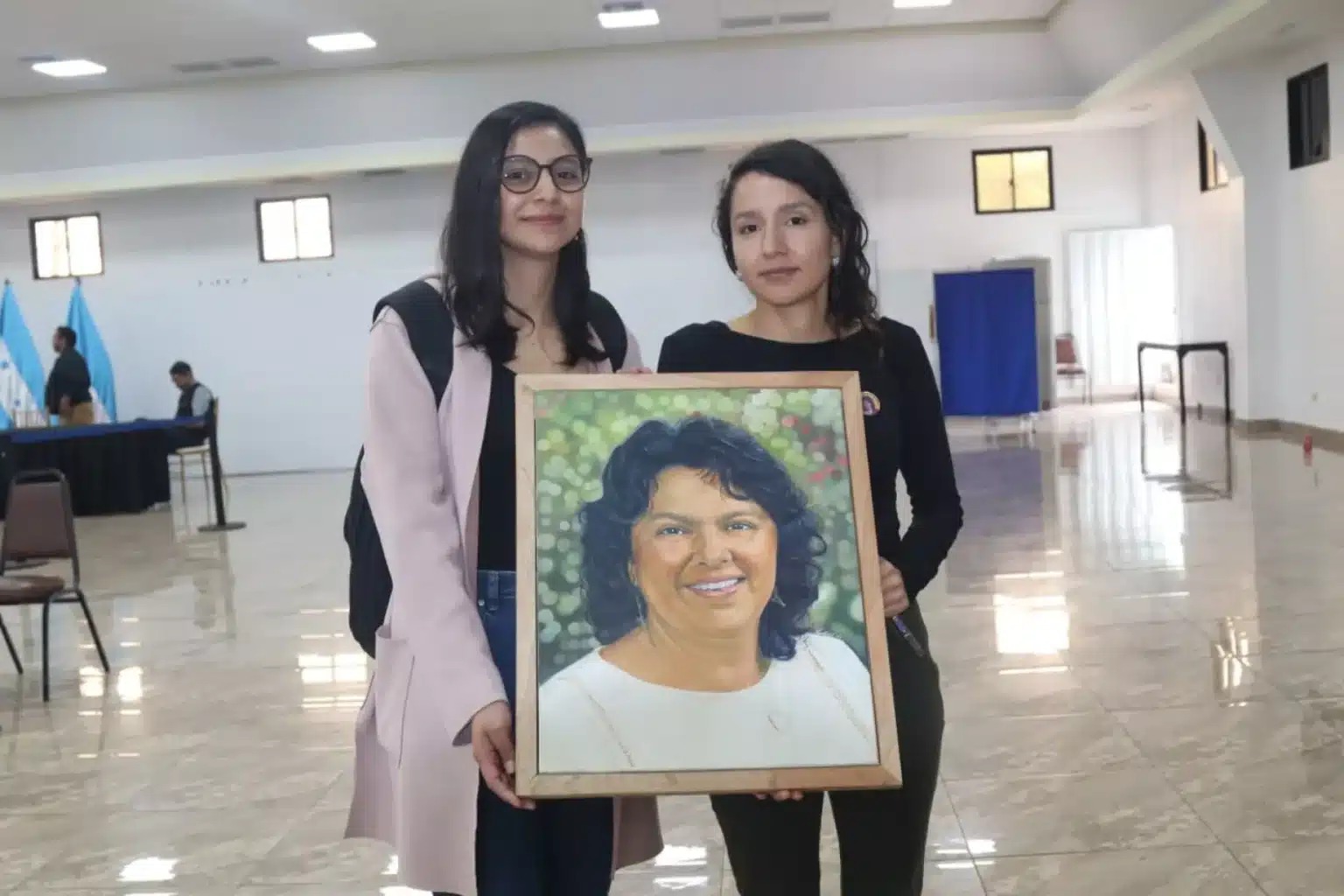 Hijas de Berta Cáceres, Berta y Laura, sostienen su retrato en la búsqueda de la justicia (© COPINH)